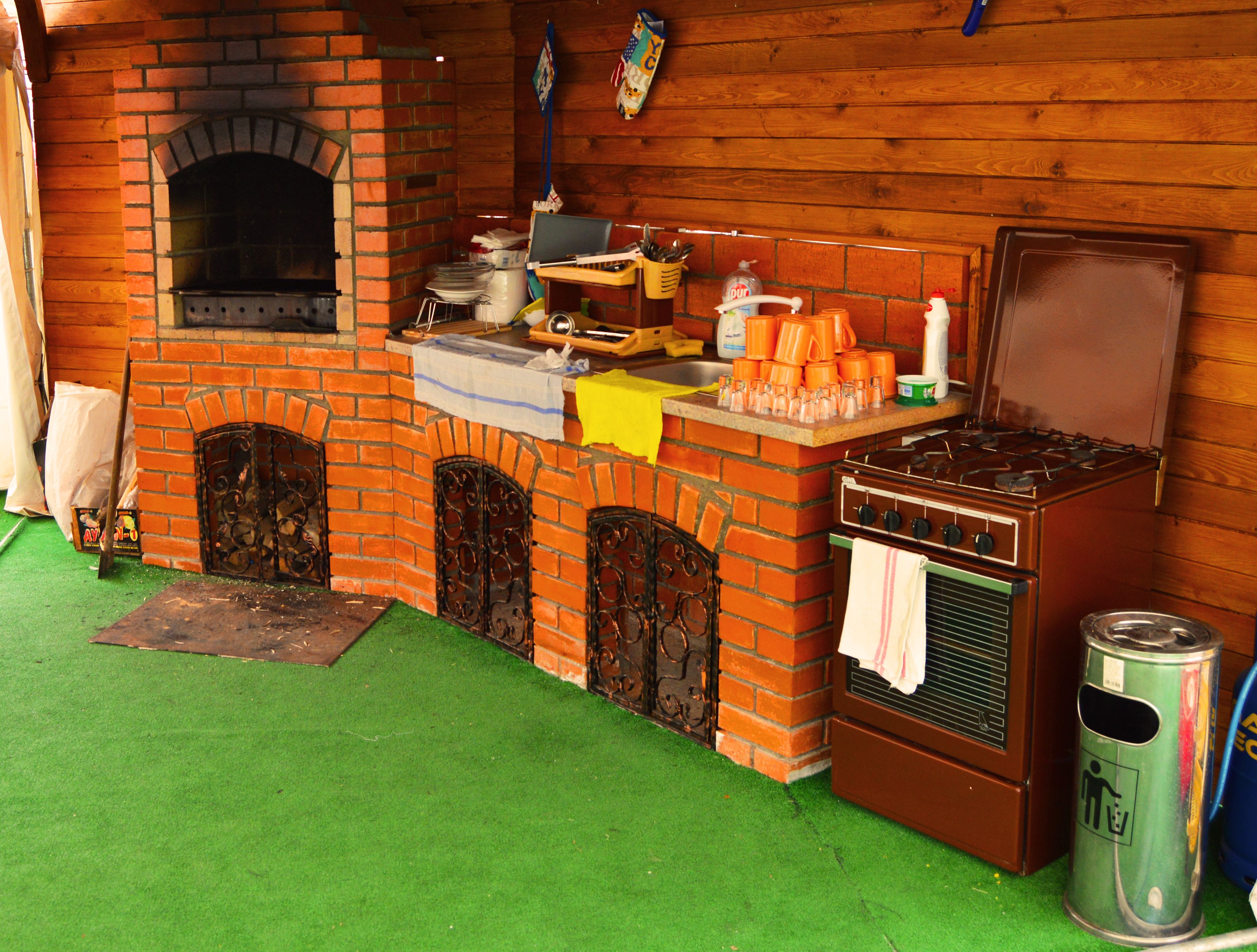 A kitchen with a brick oven, a stove, and a sink.