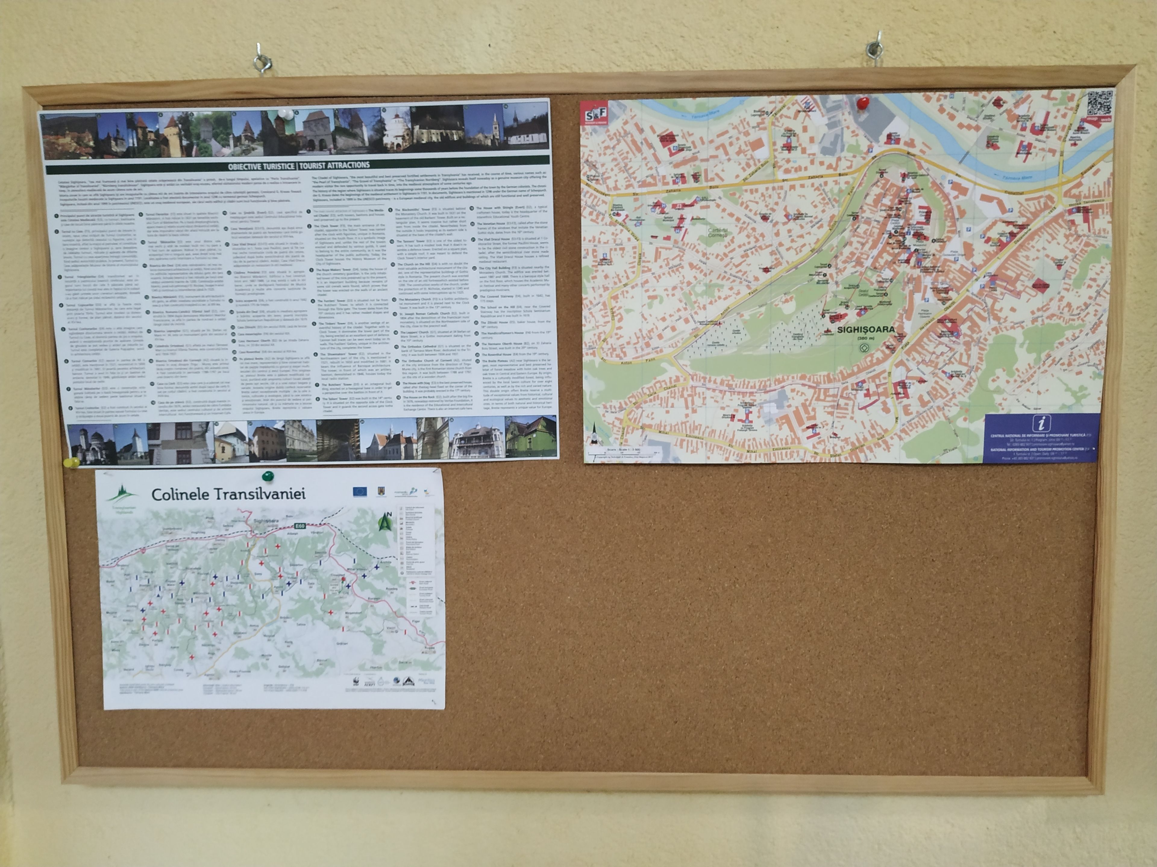 Una lavagna di sughero con tre mappe e manifesti informativi.