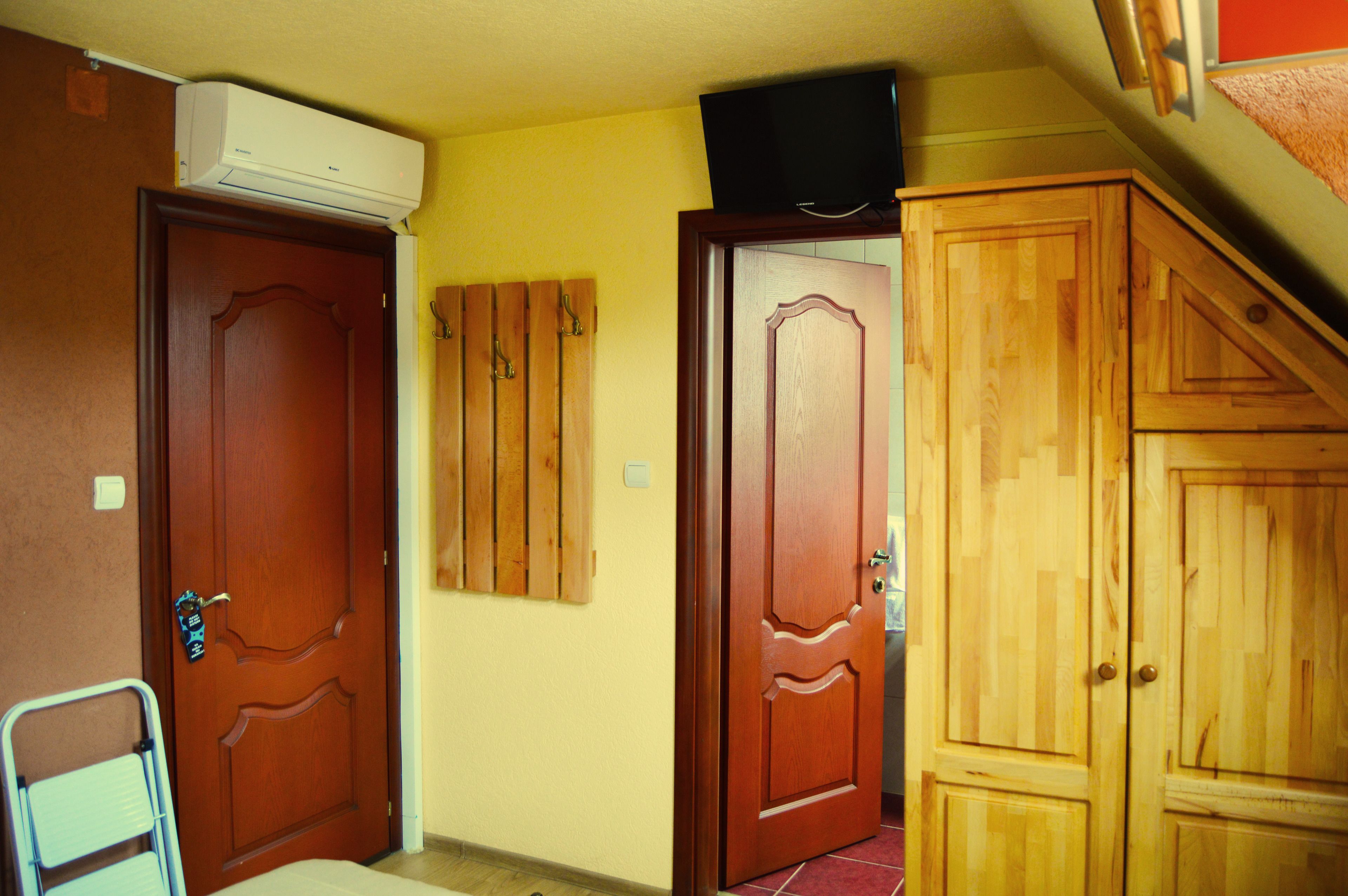 Un pasillo con puertas de madera, aire acondicionado en la pared y un televisor en el techo.
