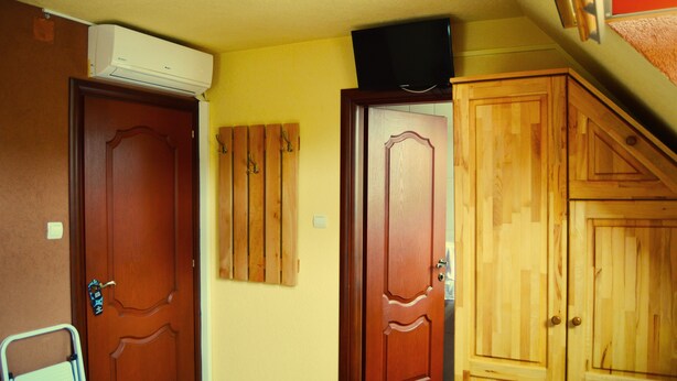 A hallway with wooden doors, a wall-mounted air conditioner, and a television on the ceiling. - Venesis House (Sighisoara)