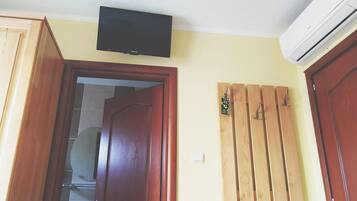 Una habitación con una puerta de madera, un televisor montado y un equipo de aire acondicionado instalado en la pared.