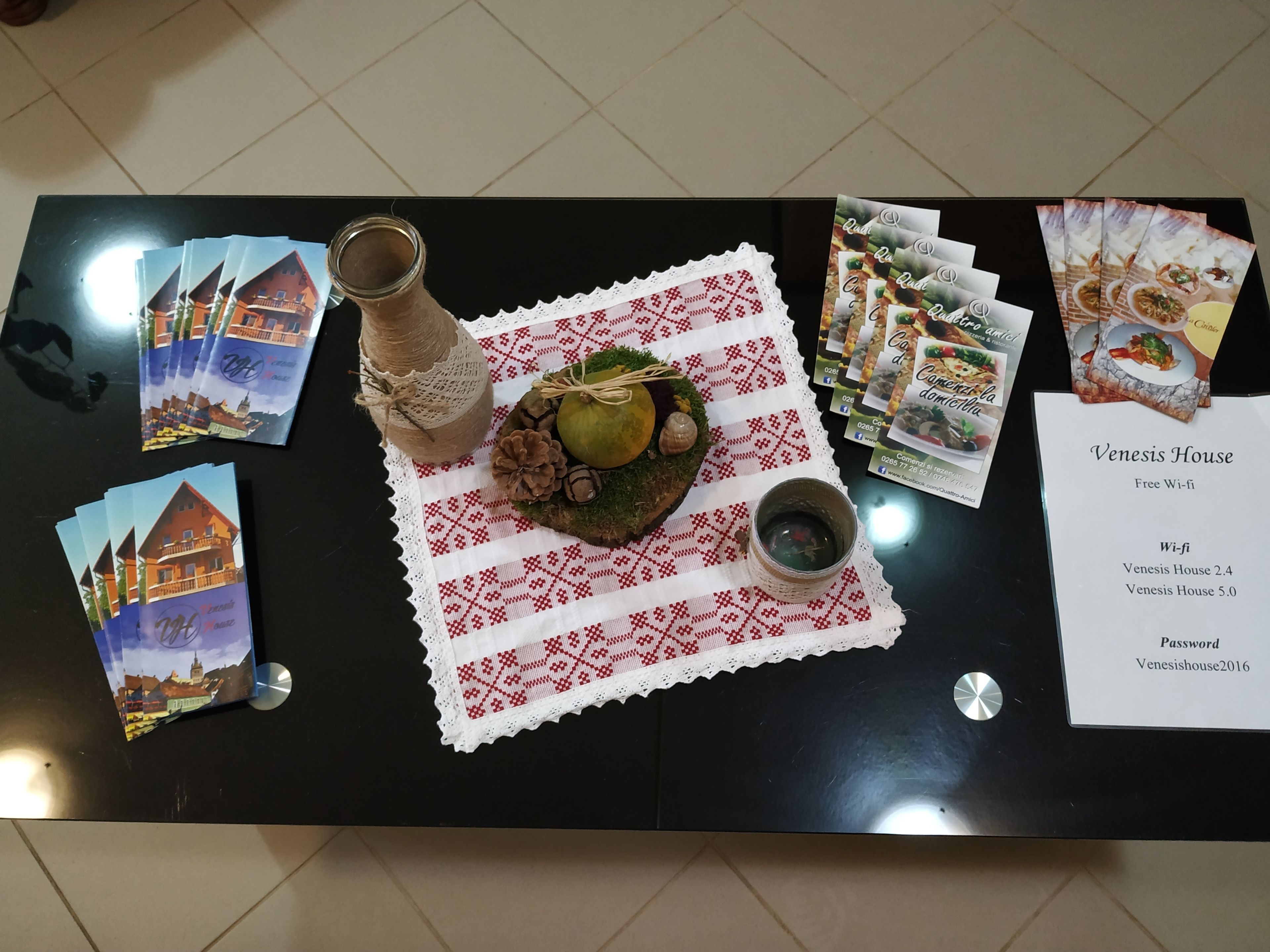Una mesa con un menú, una botella, un adorno y postales.