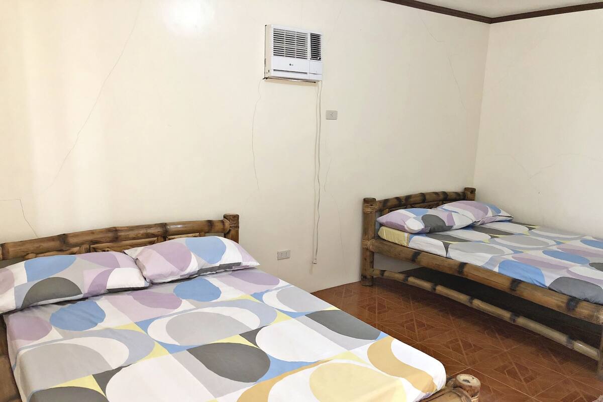 A room with two wooden beds, each with a colorful patterned bedspread.
