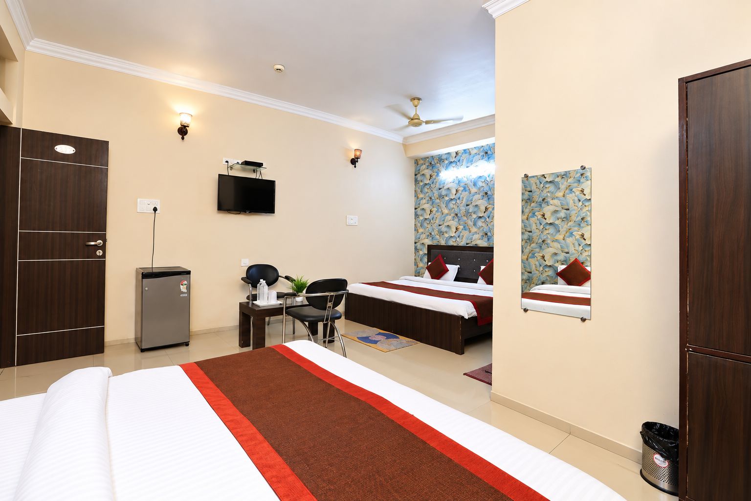 A hotel room with a bed, desk, chair, and a television.