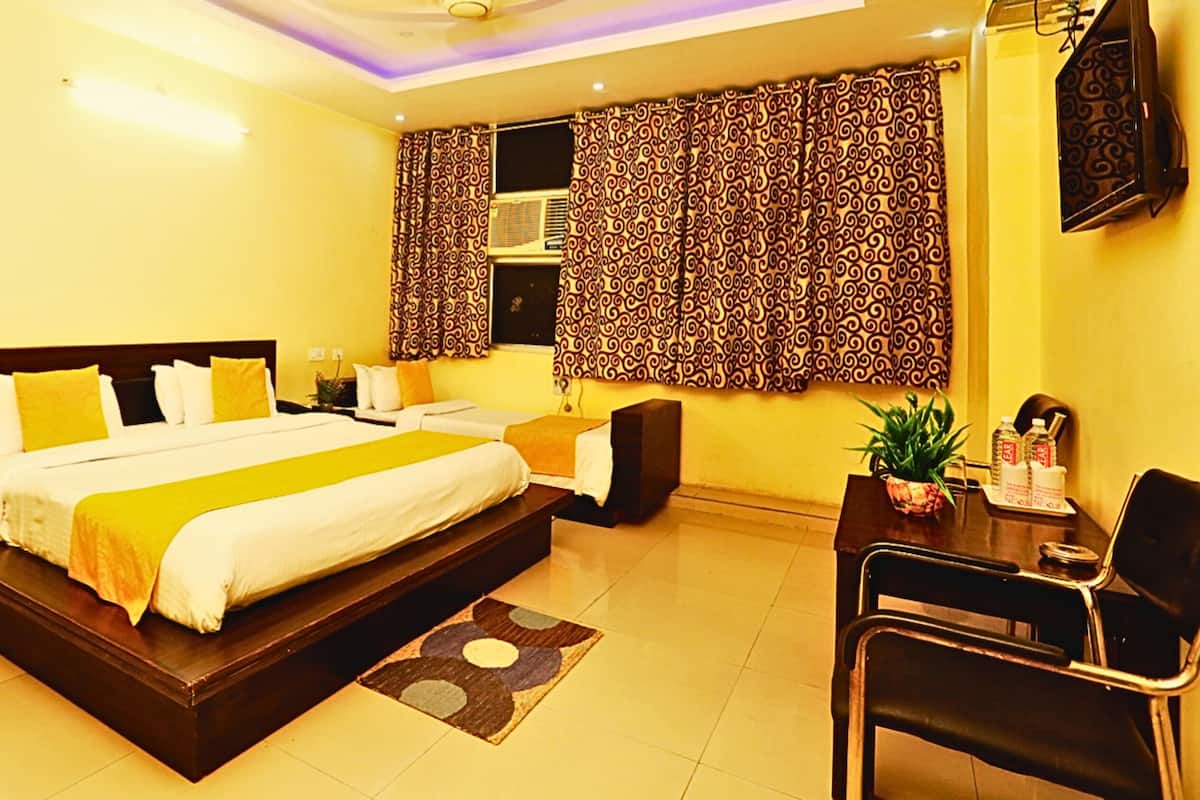 A hotel room with a large bed, a desk, a chair, and a TV.