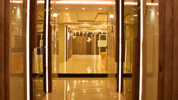 A modern hotel corridor with a shiny floor, glass walls, and warm lighting. - Hotel Nexus (Lucknow)