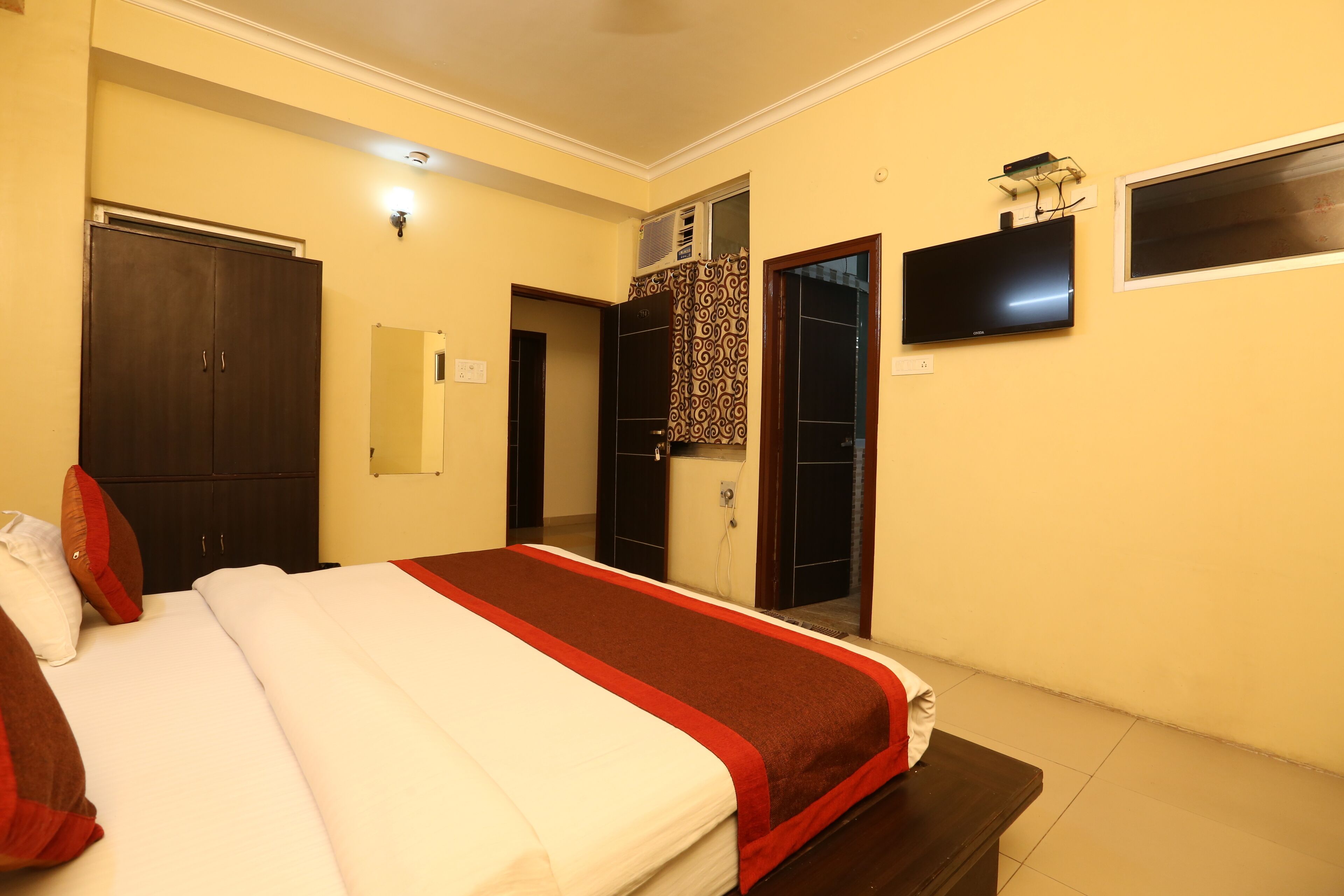 Habitación de hotel con cama, armario, televisión y espejo.