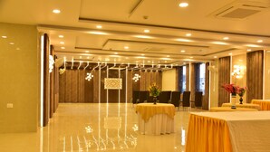 A spacious, well-lit banquet hall with polished floors, round tables with yellow tablecloths, and modern lighting fixtures. - Hotel Nexus (Lucknow)