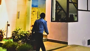 A modern building with a 'NEXUS' sign, a glass entrance, and a person walking towards it. - Hotel Nexus (Lucknow)