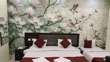 A hotel room with two beds, a nightstand, and a wall mural of flowers and birds.
