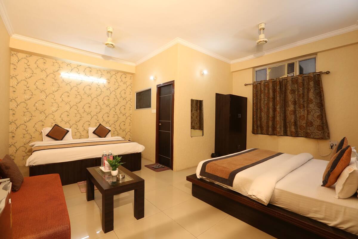 A hotel room with two beds, a desk, a chair, and a window with curtains.
