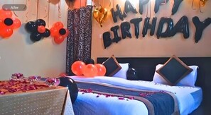Quarto com cama, almofadas e decoração com balões de 'Feliz Aniversário'.
