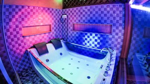 A modern bathroom with a checkered mosaic wall, a freestanding bathtub, and a built-in shower area. - Six In One (Malé)