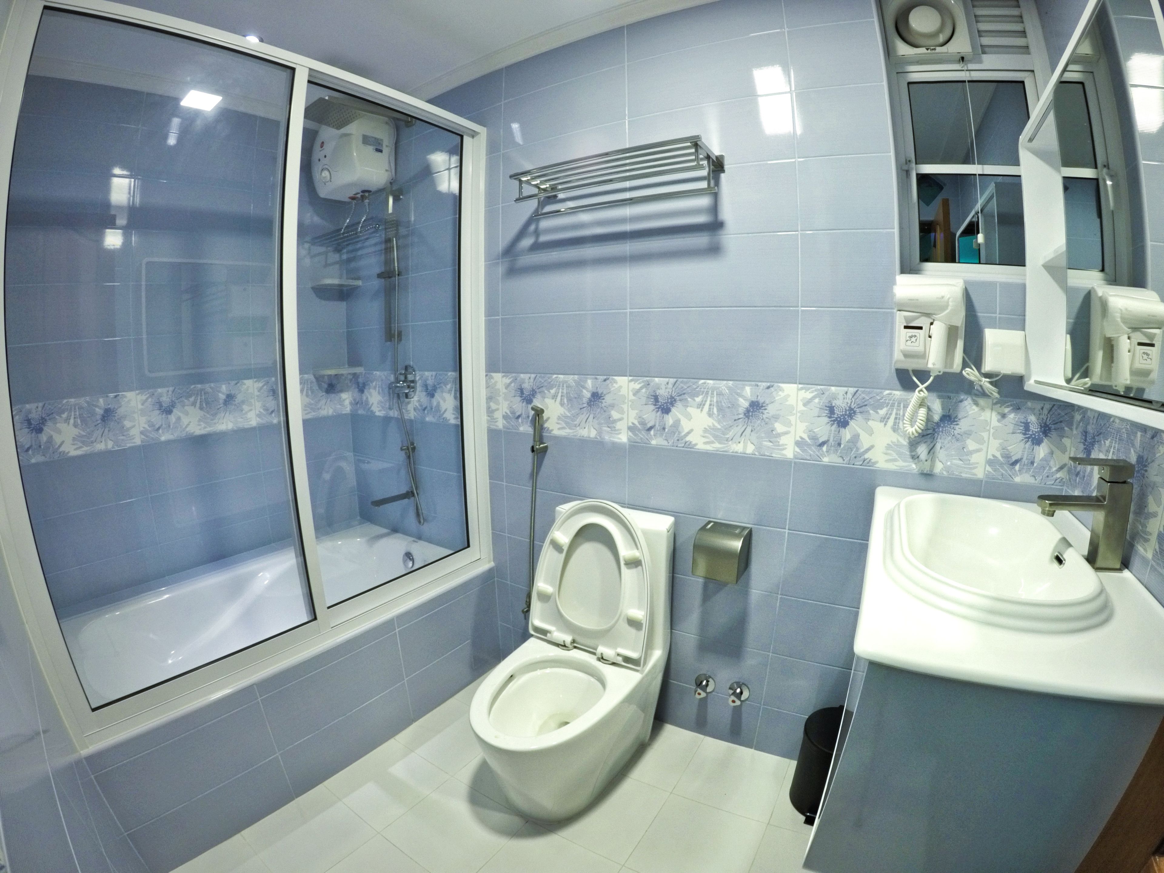 A bathroom with a shower, toilet, sink, and a mirror.
