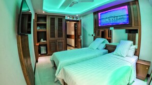 A hotel room with two beds, a TV mounted on the wall, and a ceiling fan. - Six In One (Malé)