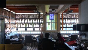 A restaurant with outdoor seating, potted plants, and a television screen. - Six In One (Malé)