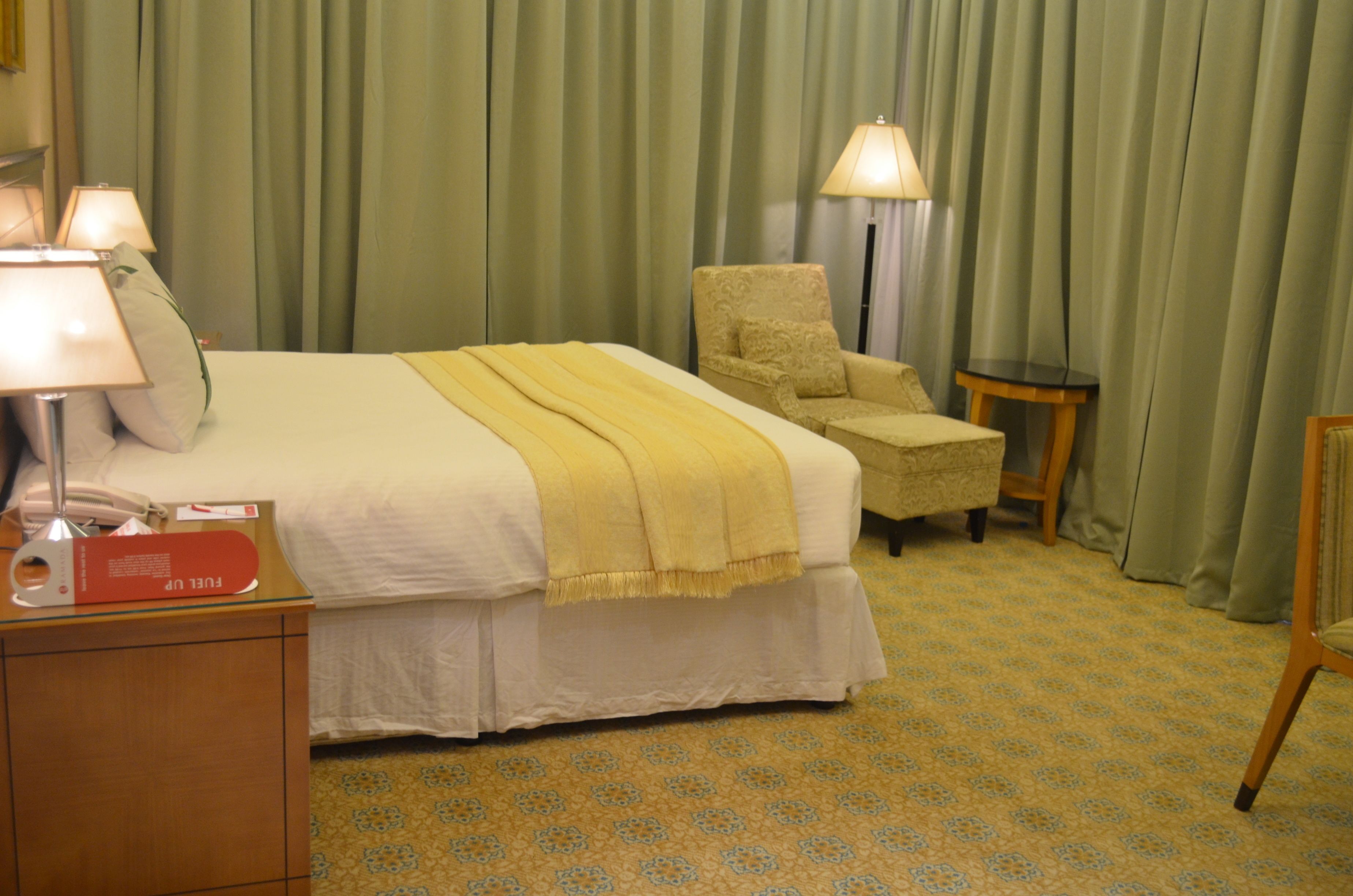 Une chambre d’hôtel avec un lit, une chaise, une lampe et une petite table.