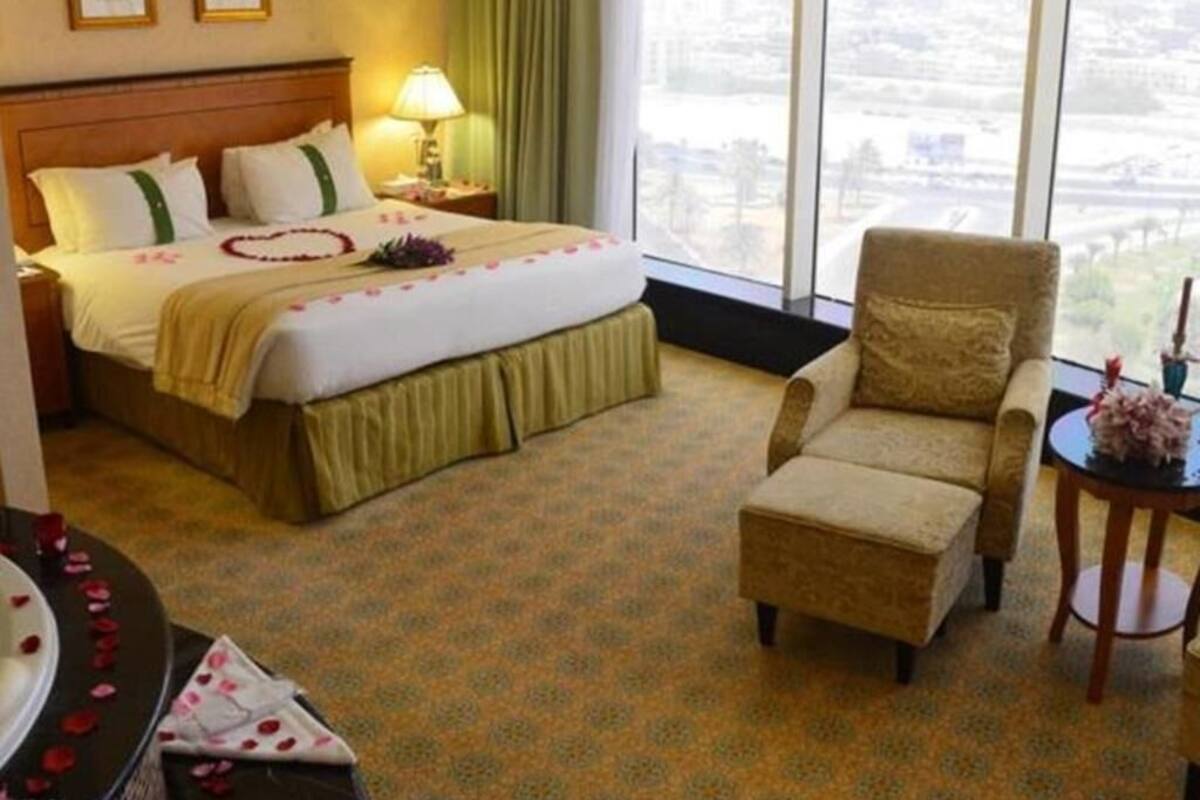 Una habitación de hotel con cama, una silla, una mesita y vistas a la ciudad.
