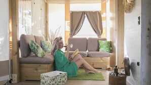 Un espacio de sala acogedor con un sofá, un caja verde con estampado y un barril de madera con botellas.