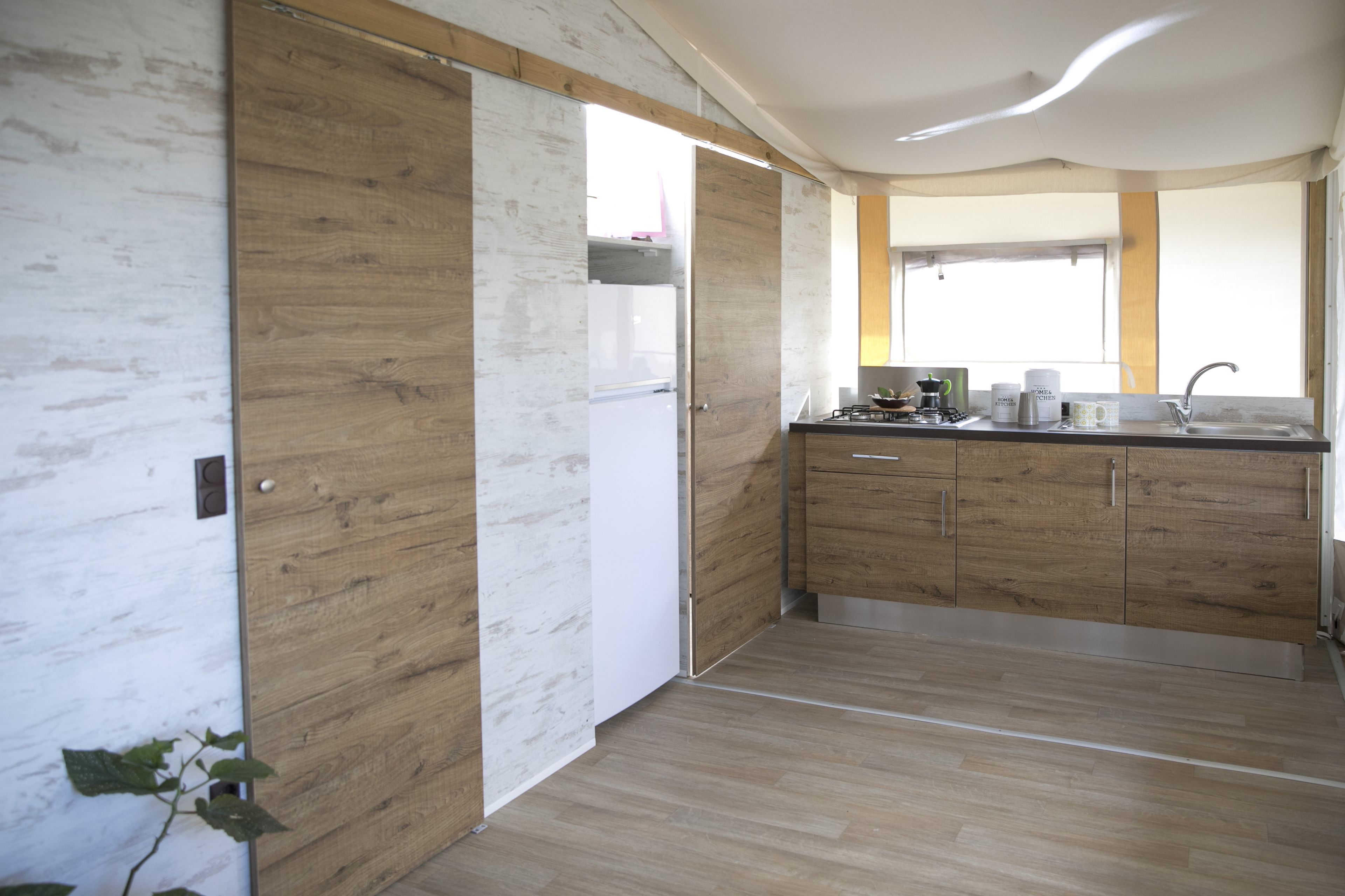 A modern kitchen with wooden cabinets, a white refrigerator, and a window providing natural light.