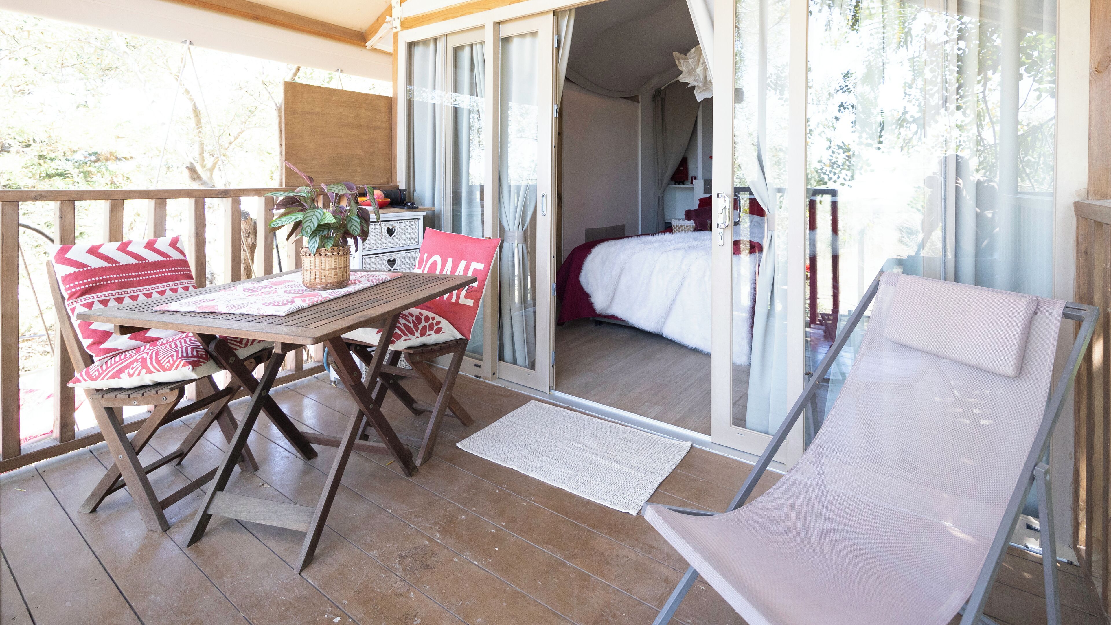 Un balcon avec une table en bois, des chaises et un banc rembourré.
