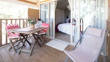 Un balcon avec une table en bois, des chaises et un banc rembourré.