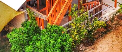 A wooden deck with a covered area, surrounded by greenery.