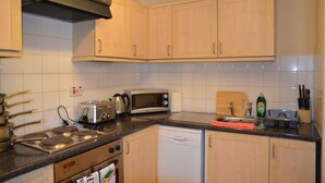 A kitchen with wooden cabinets, a microwave, a toaster, a sink, and a dishwasher. - 28 Scotfield (Luton)