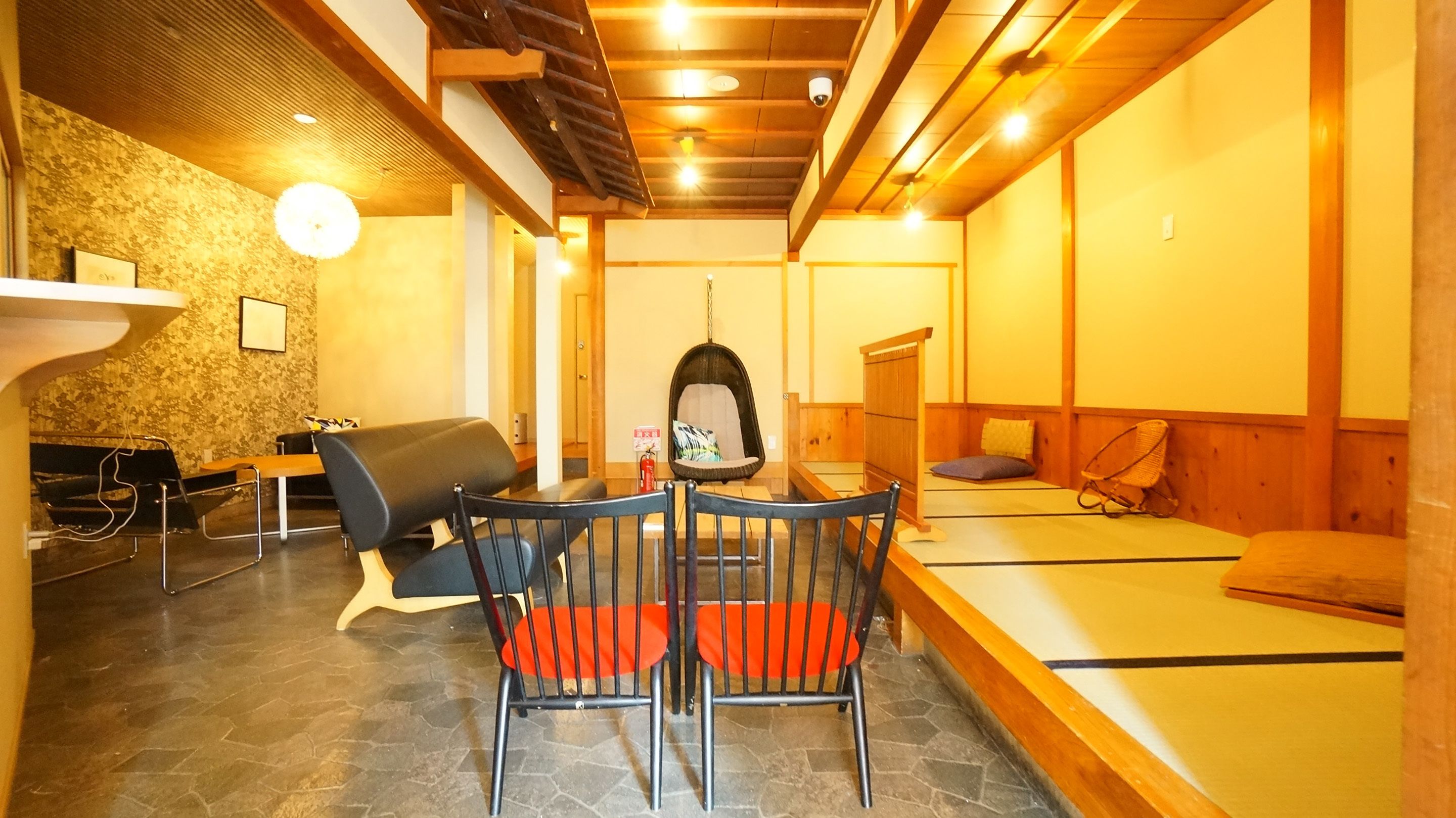 Un interior moderno con zona de comedor que incluye una mesa, sillas, un sofá y una silla colgante.