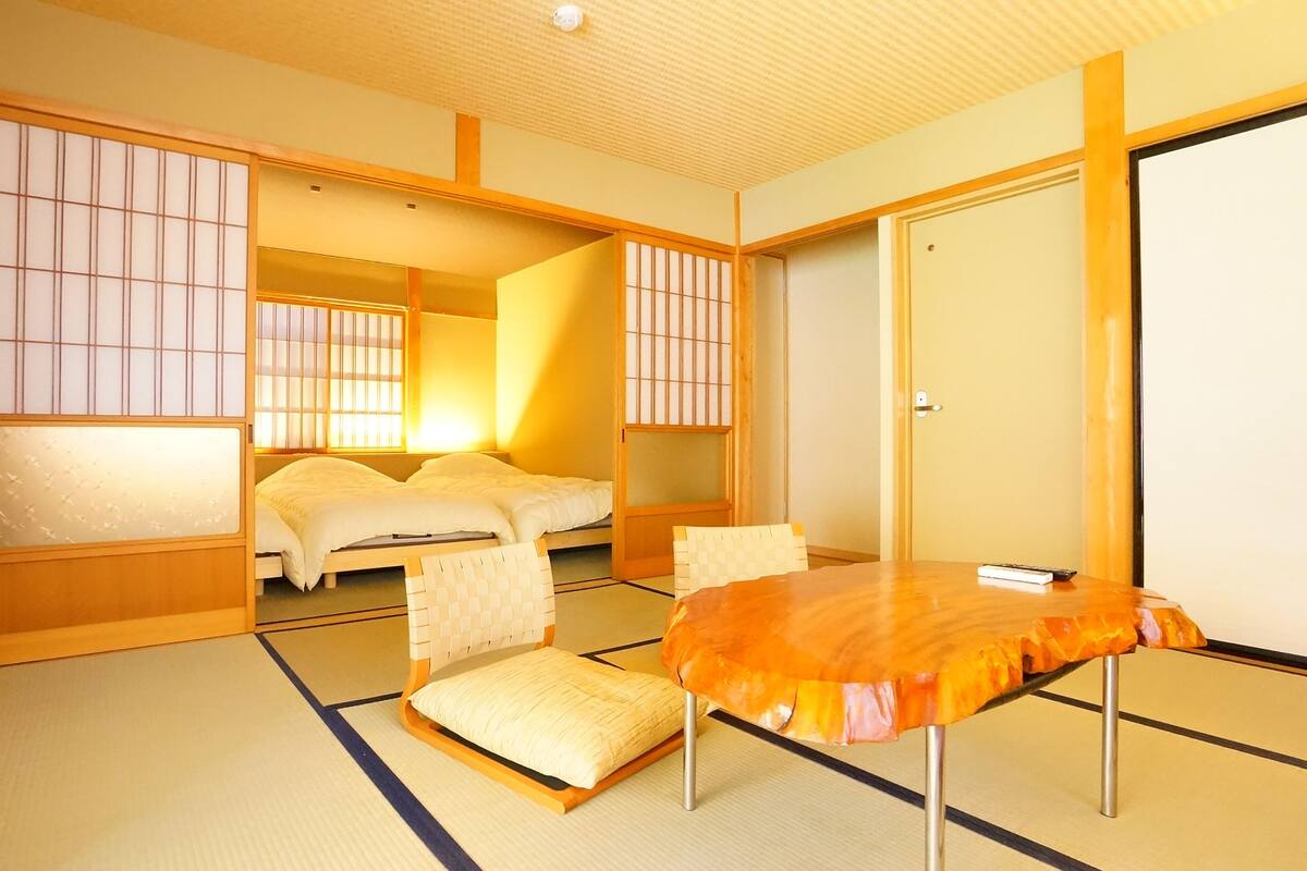 A traditional Japanese room with tatami flooring, a futon bed, a low table, and sliding shoji doors.