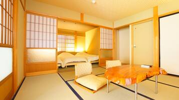 Una habitación tradicional japonesa con suelo de tatami, un futón, una mesa baja y puertas correderas shoji.