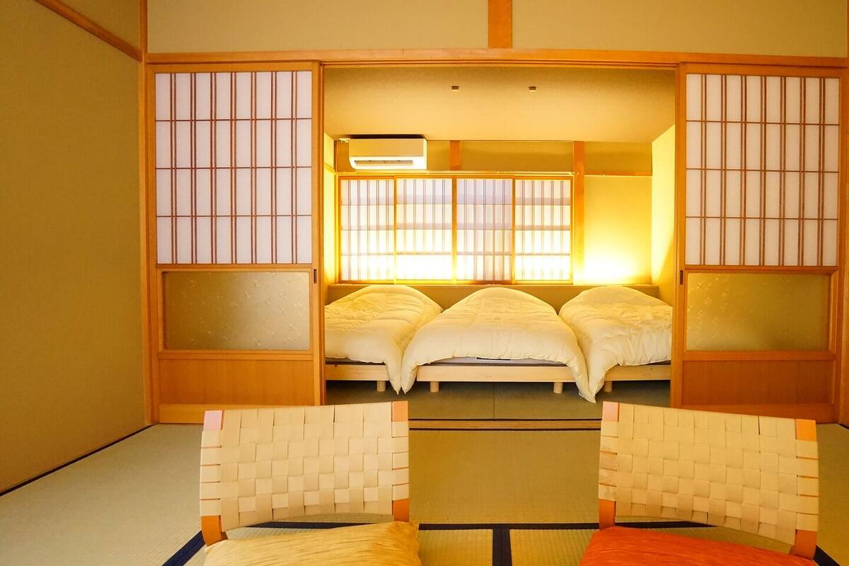 A traditional Japanese-style room with tatami flooring, a futon bed, sliding doors, and a shoji screen.