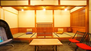 Una habitación tradicional de tatami con una mesa baja y dos sillas rojas.
