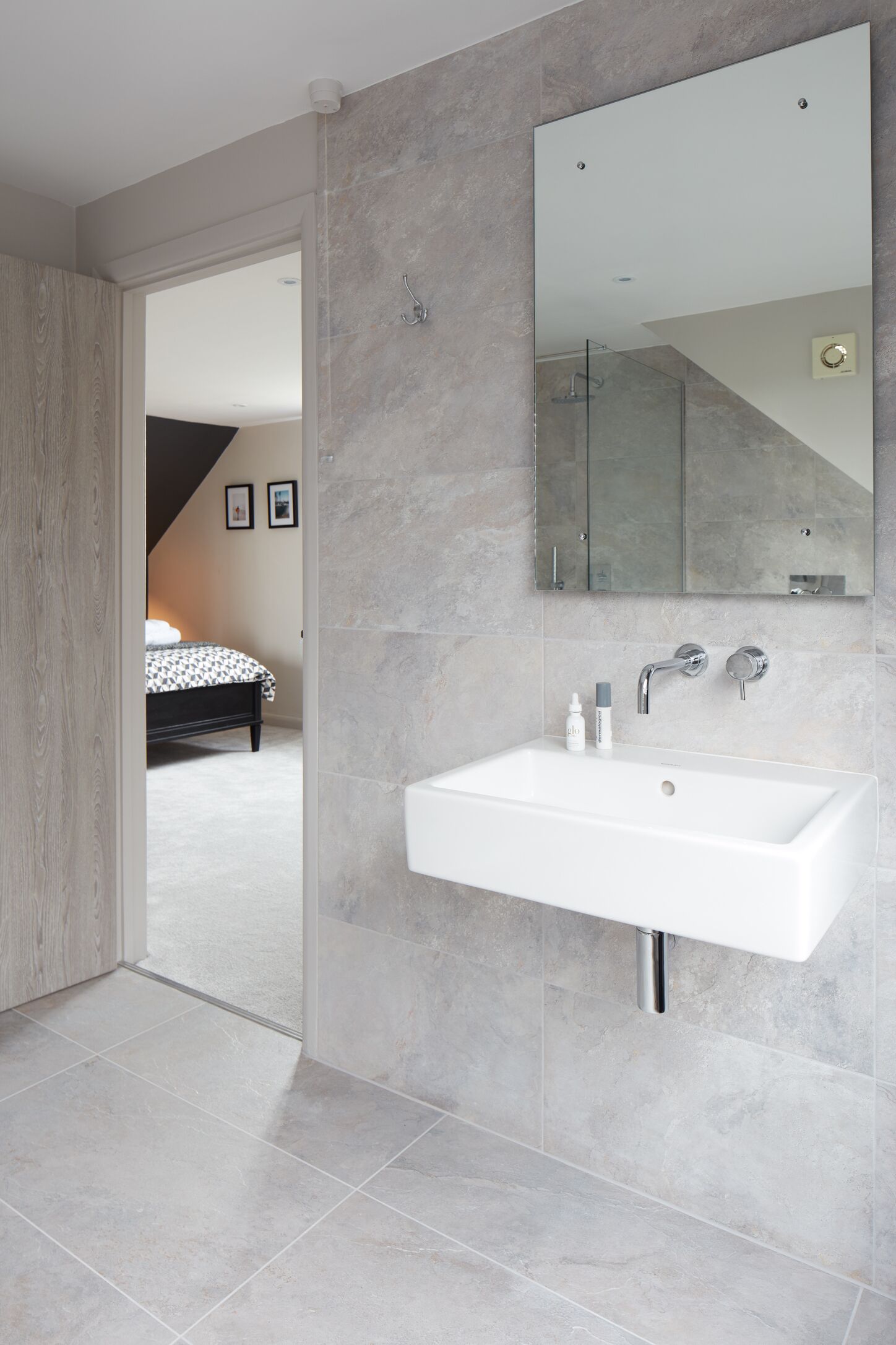 A modern bathroom with a large sink, a mirror, and a shower.