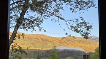 A view from a window overlooking a mountainous landscape with a lake and forested area.