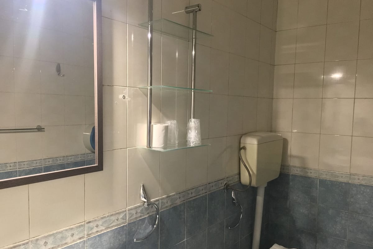 A bathroom with a glass shower enclosure, a toilet, and a sink.