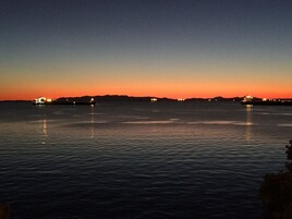 Un cuerpo de agua tranquilo al atardecer con luces distantes en barcos.