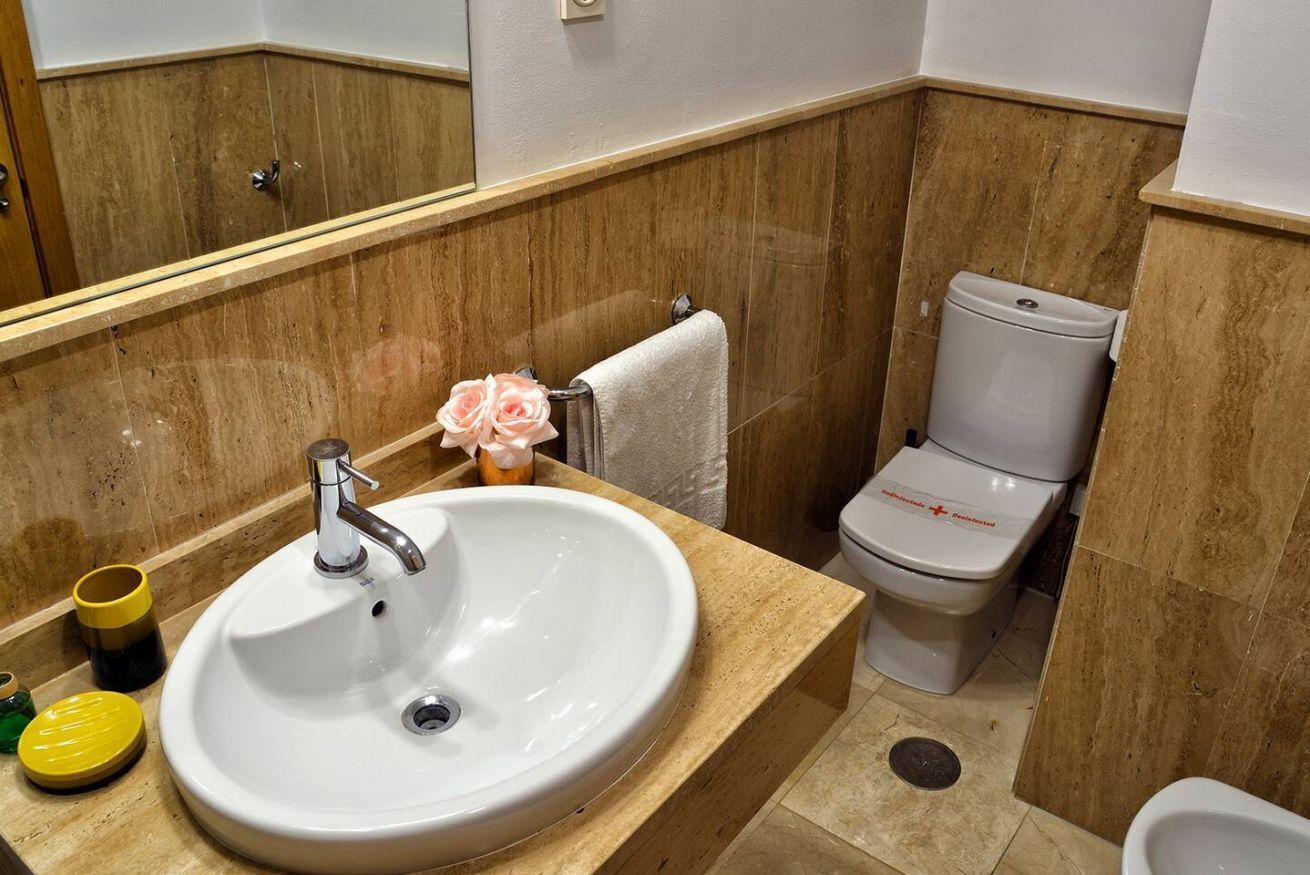 A bathroom with a white sink, a toilet, and a mirror.