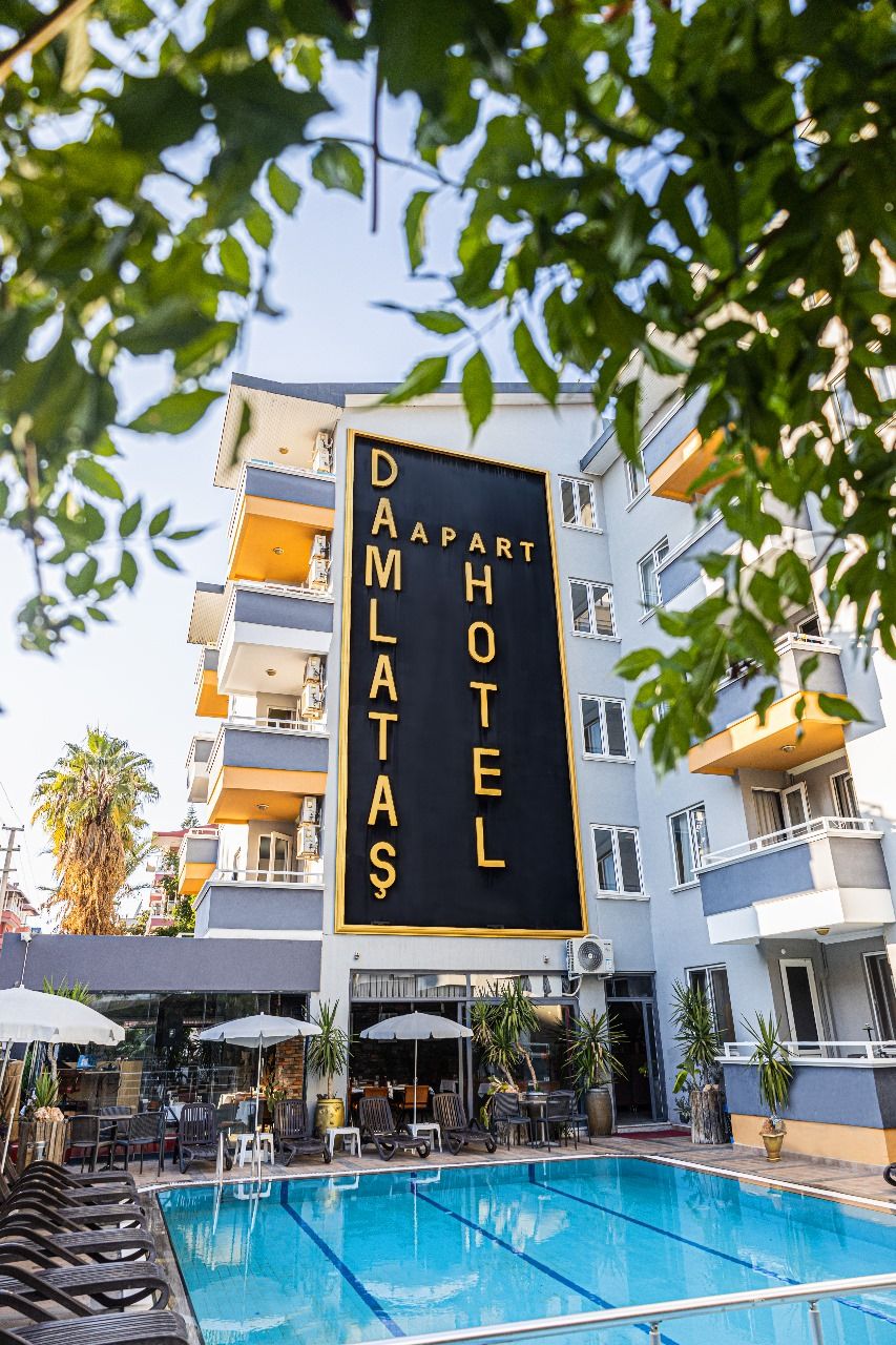 A hotel named "DAMLATAS APART HOTEL" with a pool area in front.