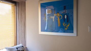 A bedroom with a bed, a pillow, a window with blinds, and a wall with a framed picture.