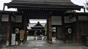 A traditional Japanese gate with wooden pillars and a tiled roof.