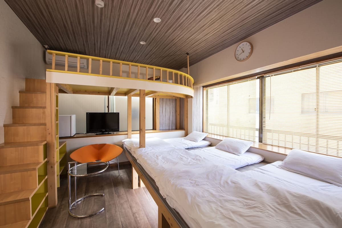 A room with a bunk bed, a desk, and a TV.