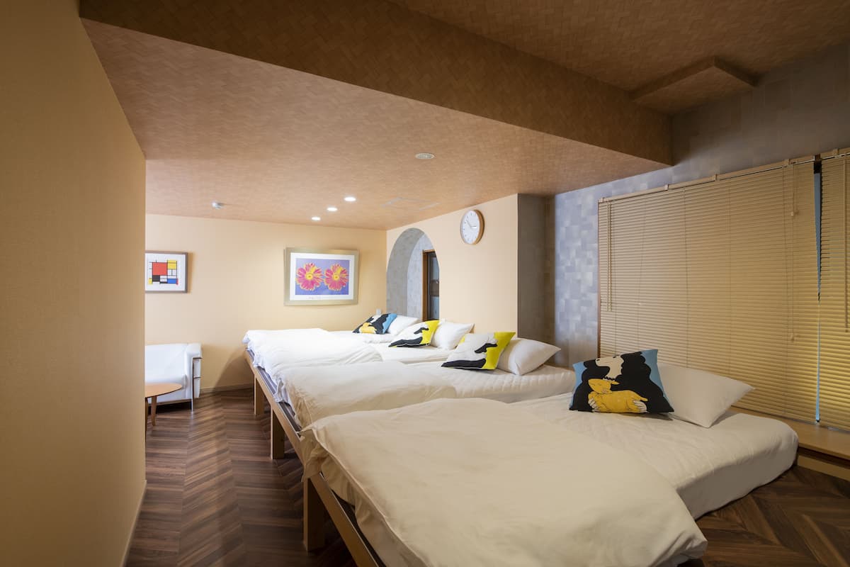 A hotel room with two beds, a small table, and a clock on the wall.