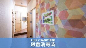 A hallway with a colorful geometric wall pattern, wooden doors, and a framed picture.