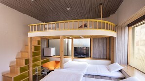 A hotel room with a loft bed, a desk, a chair, and a TV.