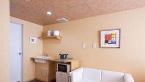 A compact living space with a kitchenette, a white sofa, and a small table.