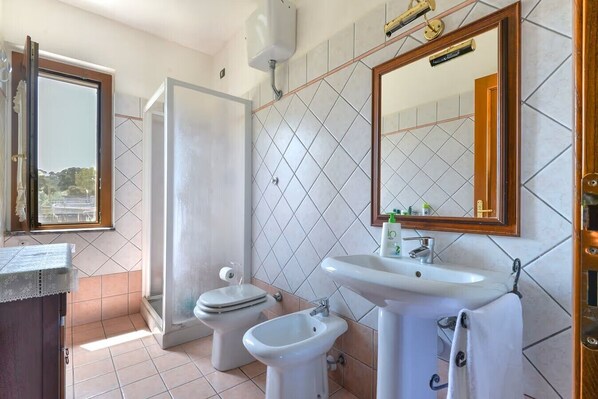 Une salle de bain comprenant des toilettes, un bidet, un lavabo et un miroir.