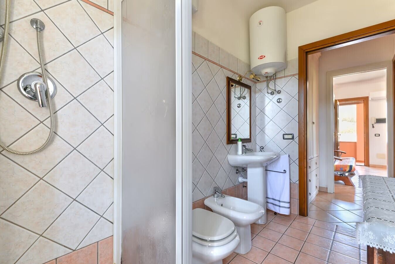 A bathroom with a shower, two toilets, a sink, and a mirror.