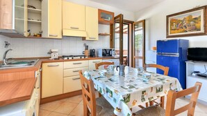 Une cuisine de taille réduite avec un coin repas, un réfrigérateur bleu et un tableau accroché au mur.