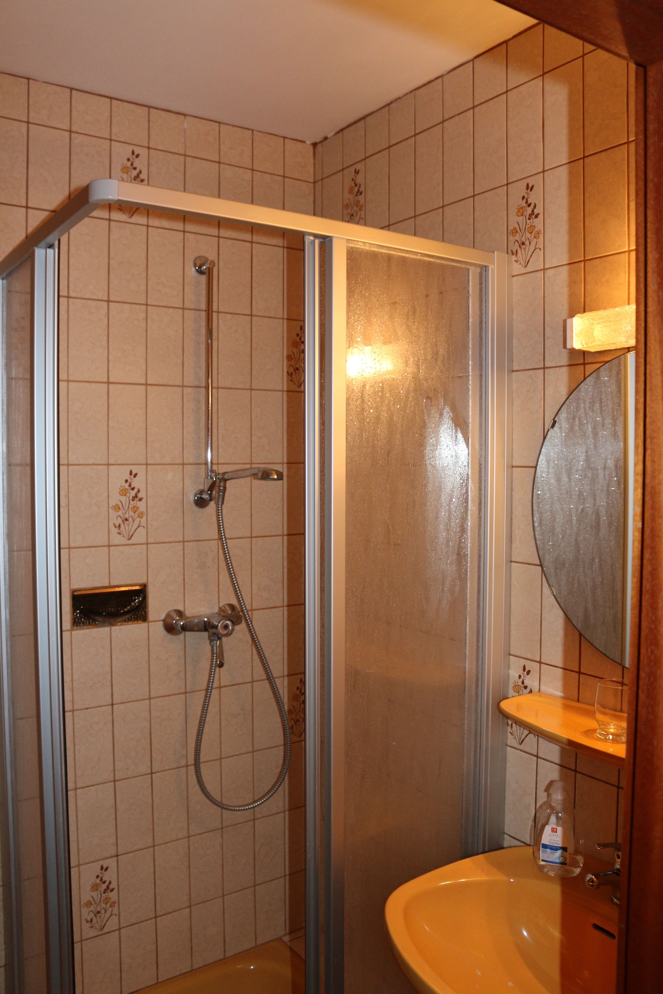 A bathroom with a shower, sink, and mirror.